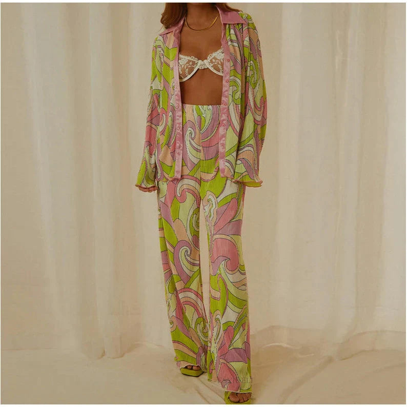 Pyjama féminin léger et confortable avec un design coloré et rétro. Le haut à manches longues et le pantalon fluide sont ornés de motifs abstraits dans des tons de rose, vert et violet. Le pyjama est élégant et parfait pour une tenue décontractée et stylée.