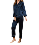 Femme portant un pyjama deux pièces en satin bleu marine, composé d’un haut à manches longues boutonné avec col à revers et passepoils contrastants, et d’un pantalon fluide assorti. Ensemble élégant, soyeux et confortable, idéal pour les nuits douces et reposantes.