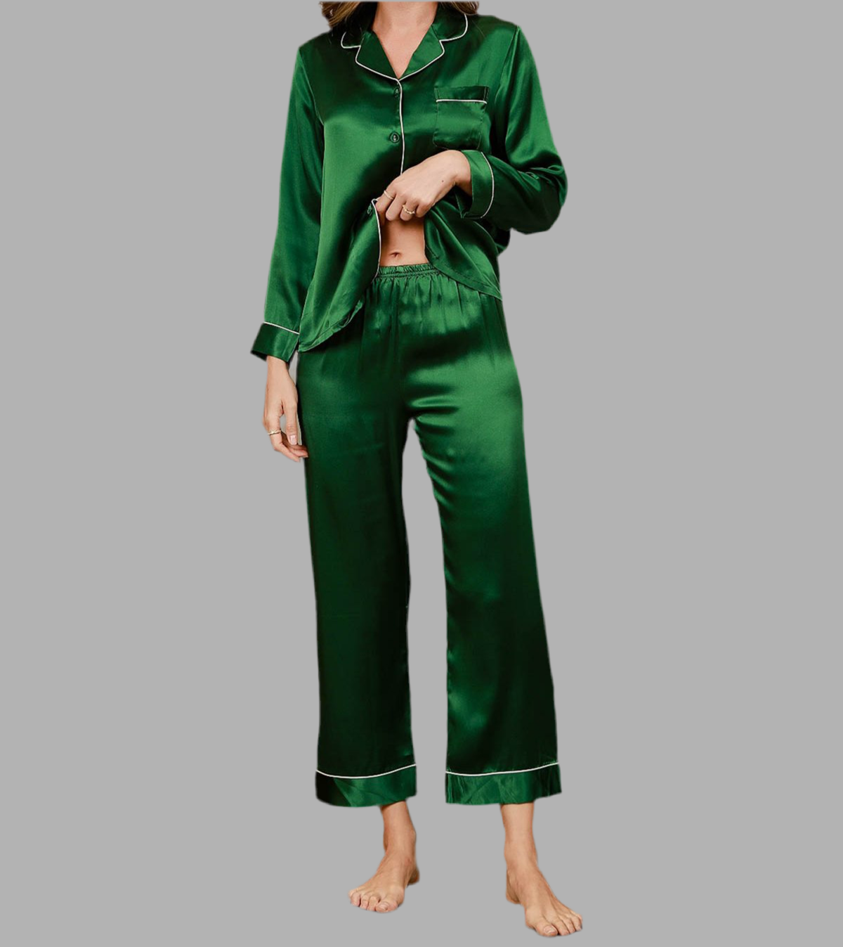 Femme portant un pyjama deux pièces en satin vert émeraude, avec haut à manches longues boutonné, col à revers et passepoils blancs, assorti d’un pantalon fluide à taille élastique. Ensemble élégant, soyeux et confortable, parfait pour des nuits paisibles avec style.