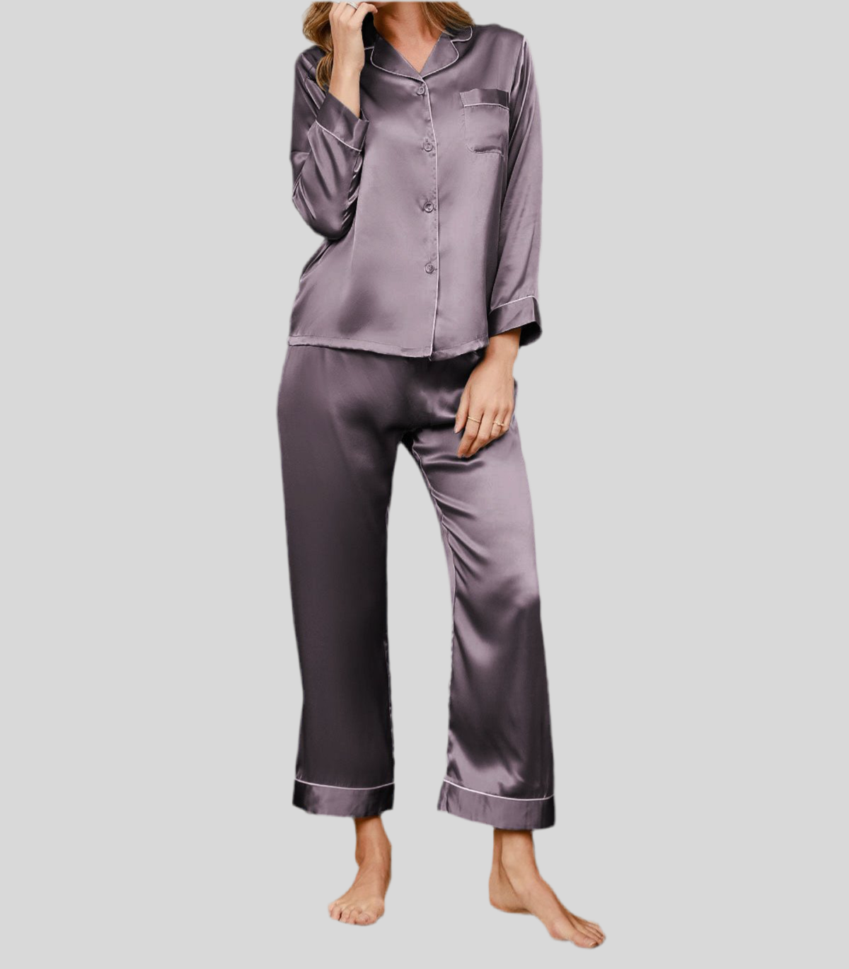 Femme portant un pyjama deux pièces en satin gris perle foncé, composé d’un haut à manches longues avec col classique, fermeture boutonnée et passepoils fins, accompagné d’un pantalon fluide assorti. Ensemble élégant, soyeux et confortable, parfait pour la nuit.