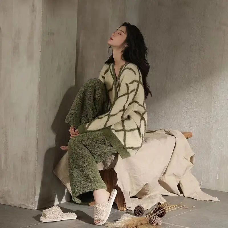 Femme assise dans une ambiance cosy, vêtue du pyjama Amélie, un ensemble élégant et tendance en tissu duveteux vert kaki avec motif géométrique, parfait pour des moments de détente stylés à la maison.