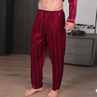 Vue de trois-quarts d’un homme portant le pantalon de pyjama en satin pour homme Amaury, pantalon bordeaux satiné à fines rayures avec taille élastique souple, coupe fluide et confortable, offrant une sensation douce, légère et élégante pour le sommeil ou les moments de détente à la maison.