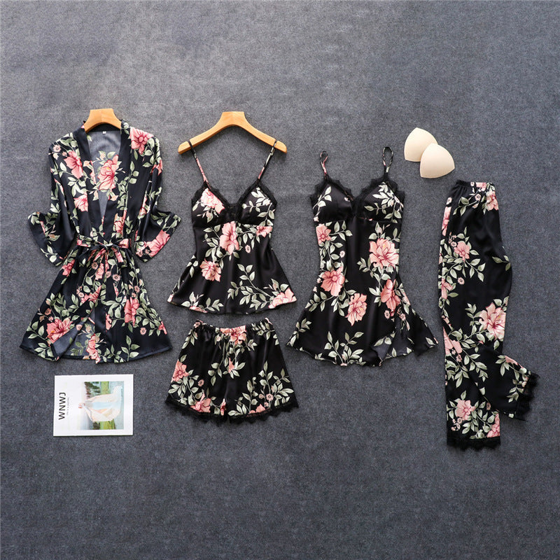 Ensemble de pyjamas femme Anaëlle, léger et confortable, composé de six pièces en satin noir à motifs floraux : kimono, haut à fines bretelles, nuisette, short, pantalon et débardeur, soigneusement disposés à plat sur un fond gris.