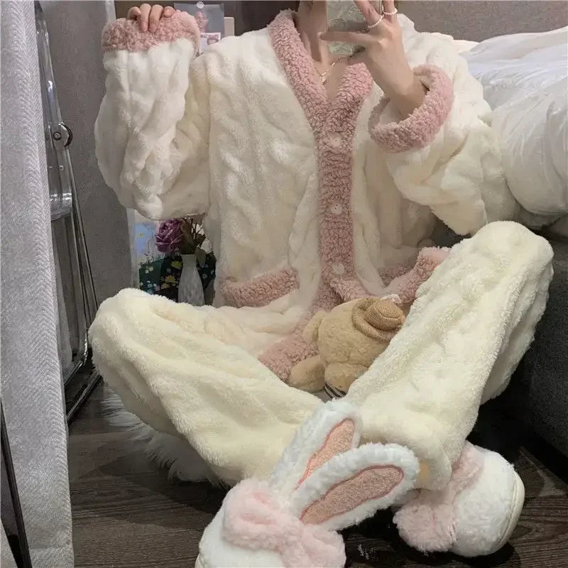 Femme assise en pyjama polaire crème avec détails roses, composé d’un haut boutonné, poches avant et finitions en tissu peluche. Elle porte des chaussons à oreilles de lapin. Tenue ultra douce et confortable, idéale pour l’hiver et les moments de détente à la maison.