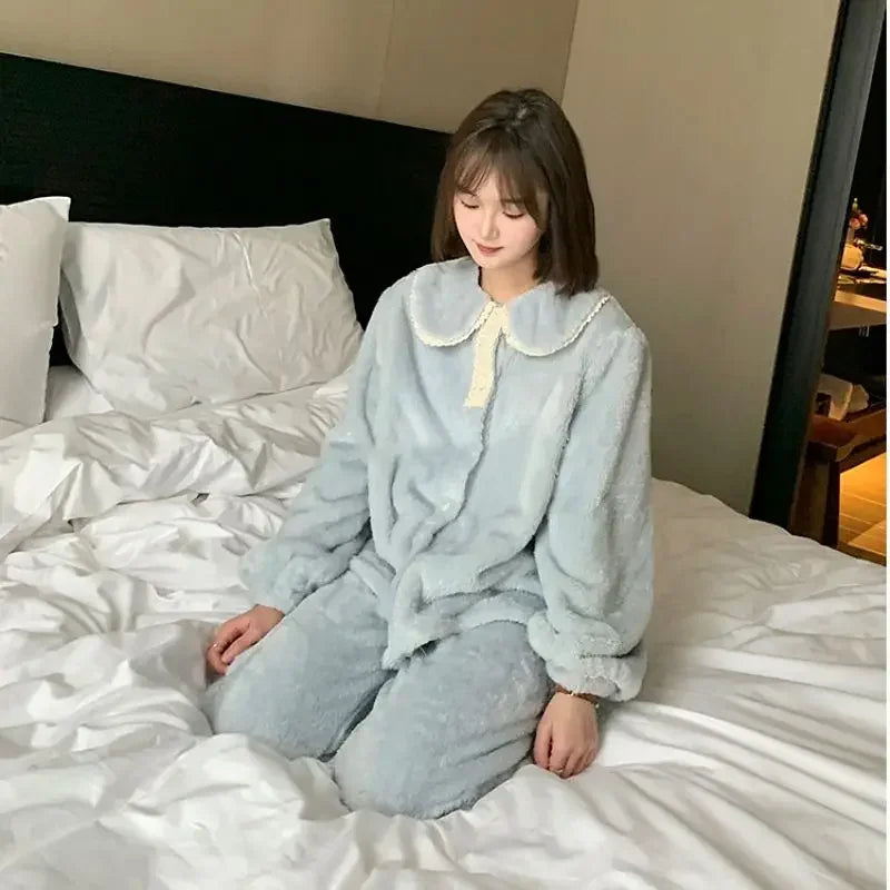 Jeune femme assise sur un lit, portant un pyjama polaire bleu clair avec col Claudine orné de dentelle crème. Ensemble deux pièces ultra doux, à manches longues, parfait pour l’hiver et les moments de détente à la maison.