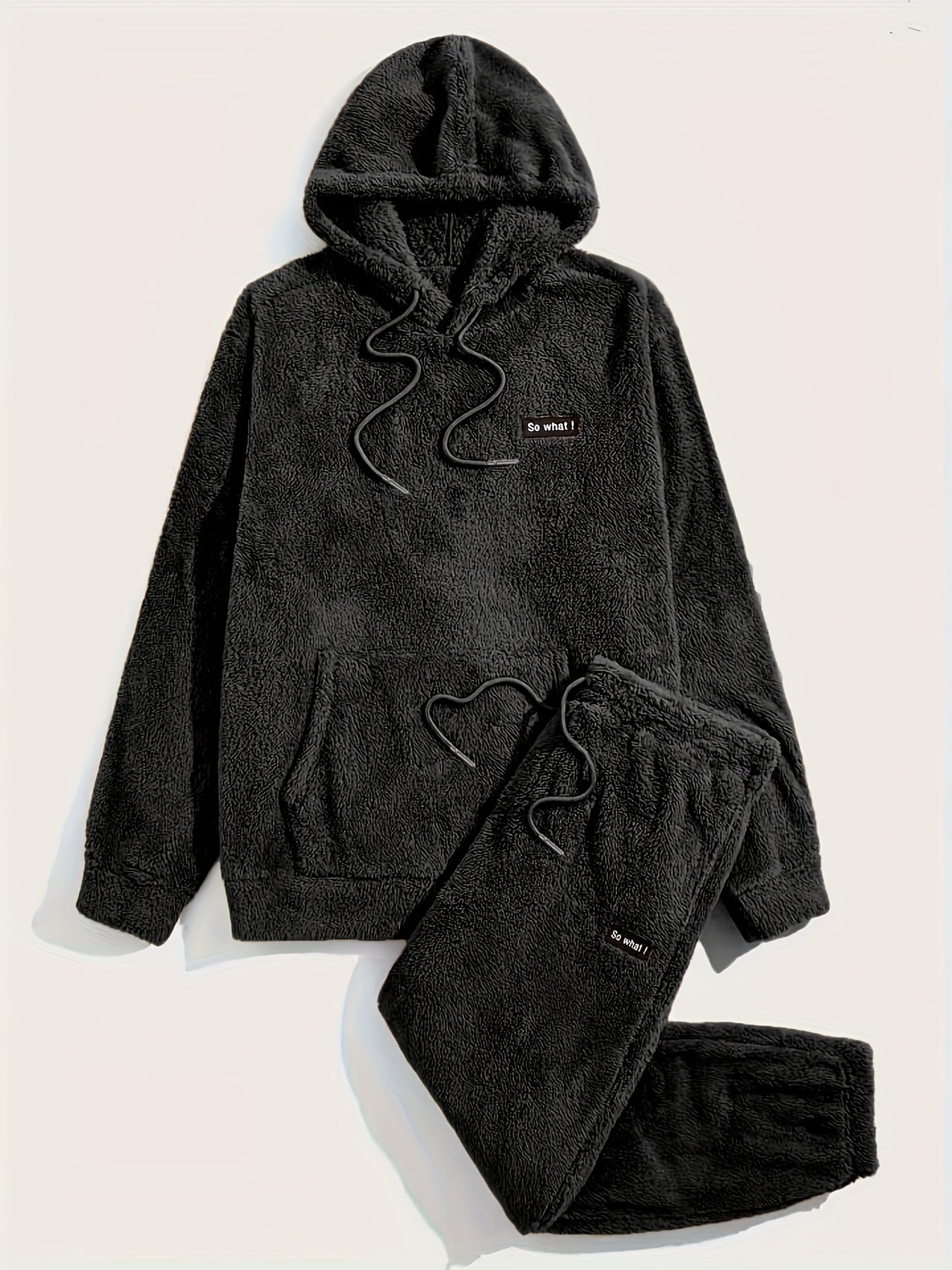 Pyjama teddy noir pour homme composé d’un haut à capuche avec cordon et d’un pantalon assorti, tous deux en tissu polaire doux et chaud. Inscription “So what !” brodée sur la poitrine et la cuisse. Ensemble confortable, parfait pour l’hiver et les moments de détente à la maison.