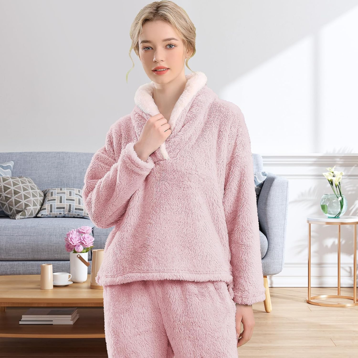 Femme portant un pyjama polaire rose poudré composé d’un haut doux à col large doublé en sherpa blanc et d’un pantalon assorti. Ensemble chaud, moelleux et très confortable, idéal pour l’hiver et les moments cocooning à la maison.