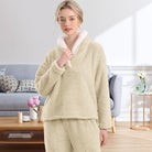 Femme portant un pyjama polaire beige sable composé d’un haut doux à col large doublé en sherpa blanc et d’un pantalon assorti. Ensemble chaud, moelleux et très confortable, idéal pour l’hiver et les moments cocooning à la maison.