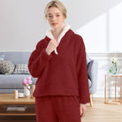 Femme portant un pyjama polaire rouge bordeaux composé d’un haut doux à col large doublé en sherpa blanc et d’un pantalon assorti. Ensemble chaud, moelleux et très confortable, parfait pour l’hiver et les moments cocooning à la maison.