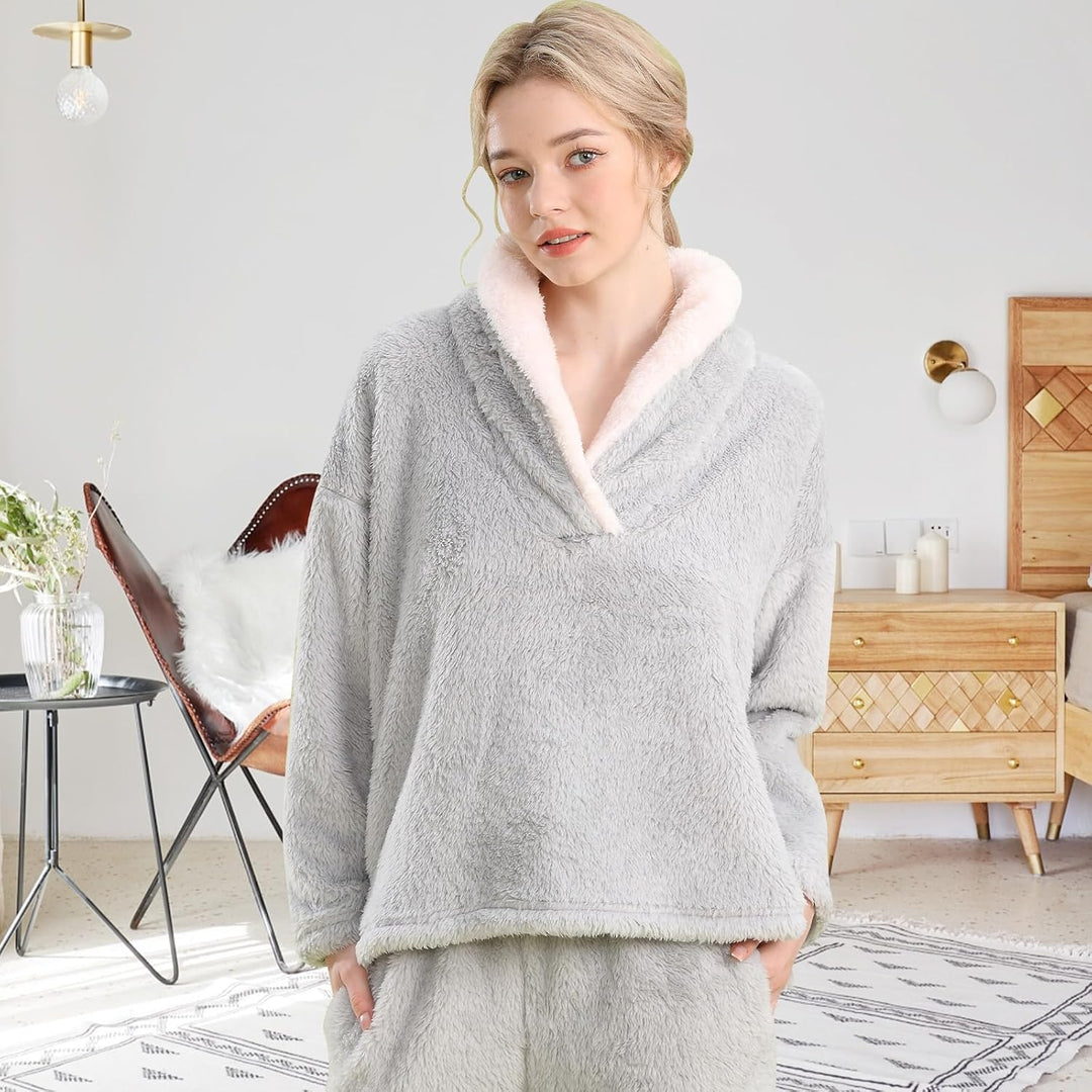 Femme portant un pyjama polaire gris clair composé d’un haut doux à col large doublé en sherpa blanc et d’un pantalon assorti. Ensemble chaud, moelleux et très confortable, idéal pour l’hiver et les moments cocooning à la maison.
