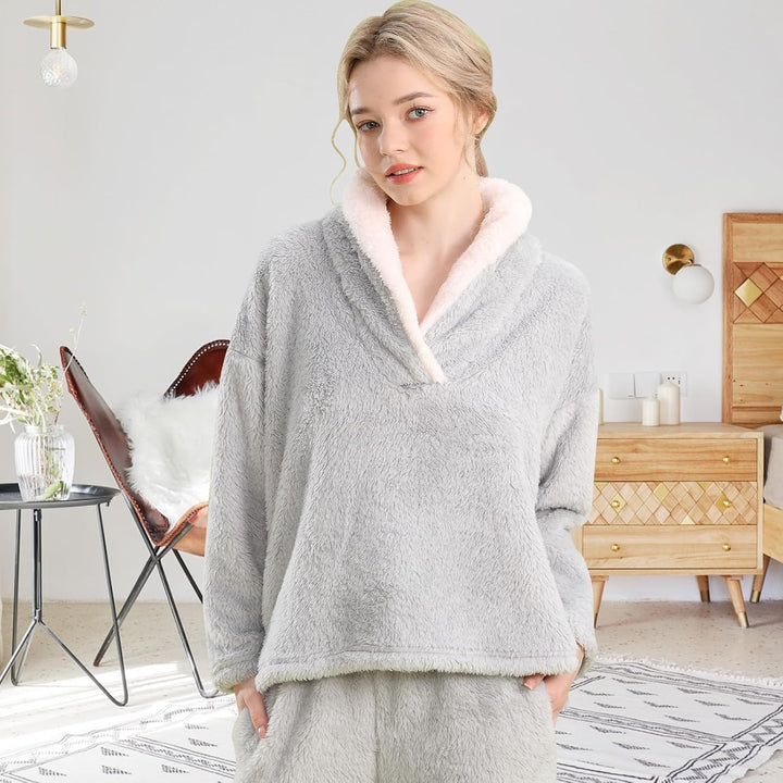 Femme portant un pyjama polaire gris clair composé d’un haut doux à col large doublé en sherpa blanc et d’un pantalon assorti. Ensemble chaud, moelleux et très confortable, idéal pour l’hiver et les moments cocooning à la maison.