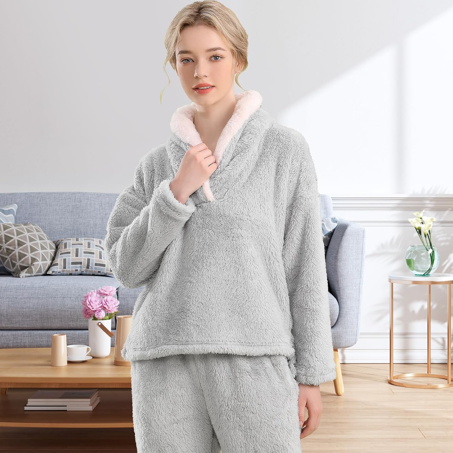 Femme portant un pyjama polaire gris clair composé d’un haut doux à col large doublé en sherpa blanc et d’un pantalon assorti. Ensemble chaud, moelleux et très confortable, idéal pour l’hiver et les moments cocooning à la maison.