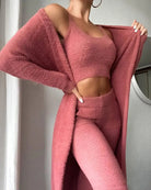 Ensemble femme en tricot rose composé d’un pantalon taille haute, d’un crop top sans manches et d’un long gilet assorti. La matière douce et extensible offre un confort optimal tout en mettant en valeur la silhouette pour un style cosy, tendance et féminin à la maison.