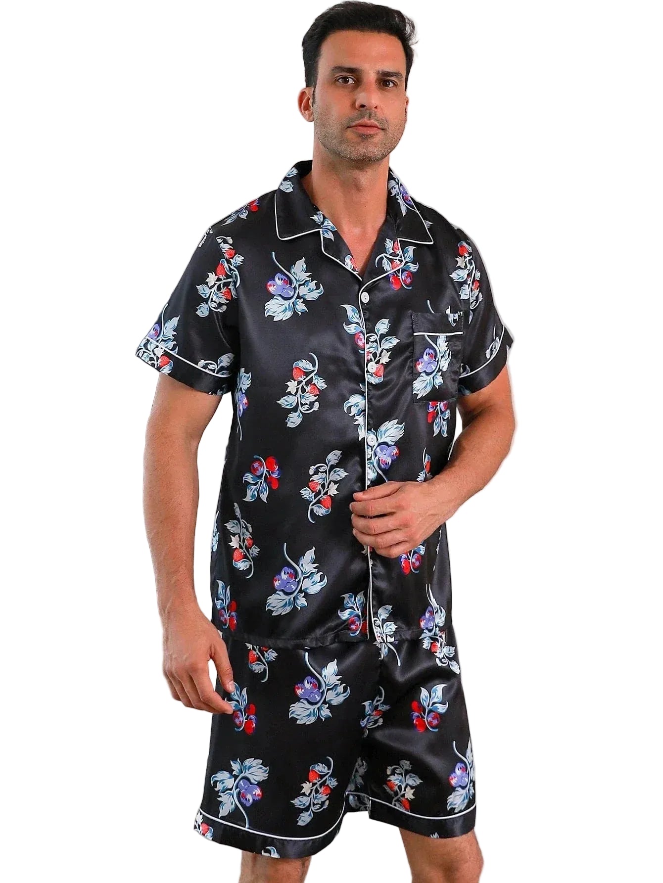 Homme debout portant le pyjama satin Armand pour homme, ensemble deux pièces avec chemise à manches courtes et short assorti, coloris noir à imprimé floral et fruits rouges, finitions contrastées et aspect satiné, présenté sur fond blanc.