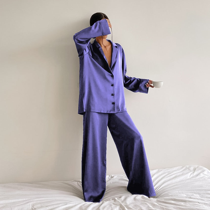 Pyjama femme Armelle violet, ensemble deux pièces raffiné et confortable avec chemise fluide boutonnée à col tailleur et manches longues, pantalon large assorti, porté debout en intérieur, tissu satiné élégant.