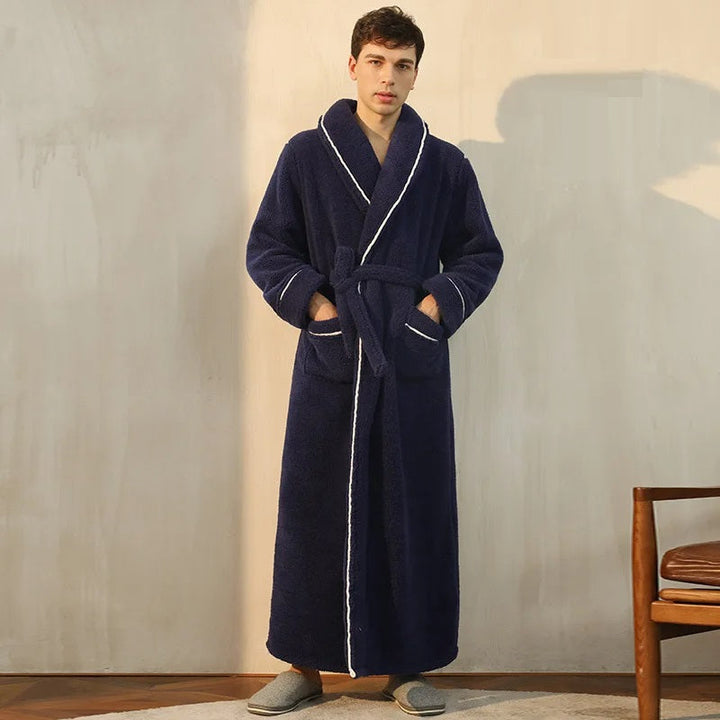 un peignoir long bleu marine en tissu peluche ultra-doux avec ceinture et poches avant, offrant un confort chaleureux idéal pour la saison froide.
