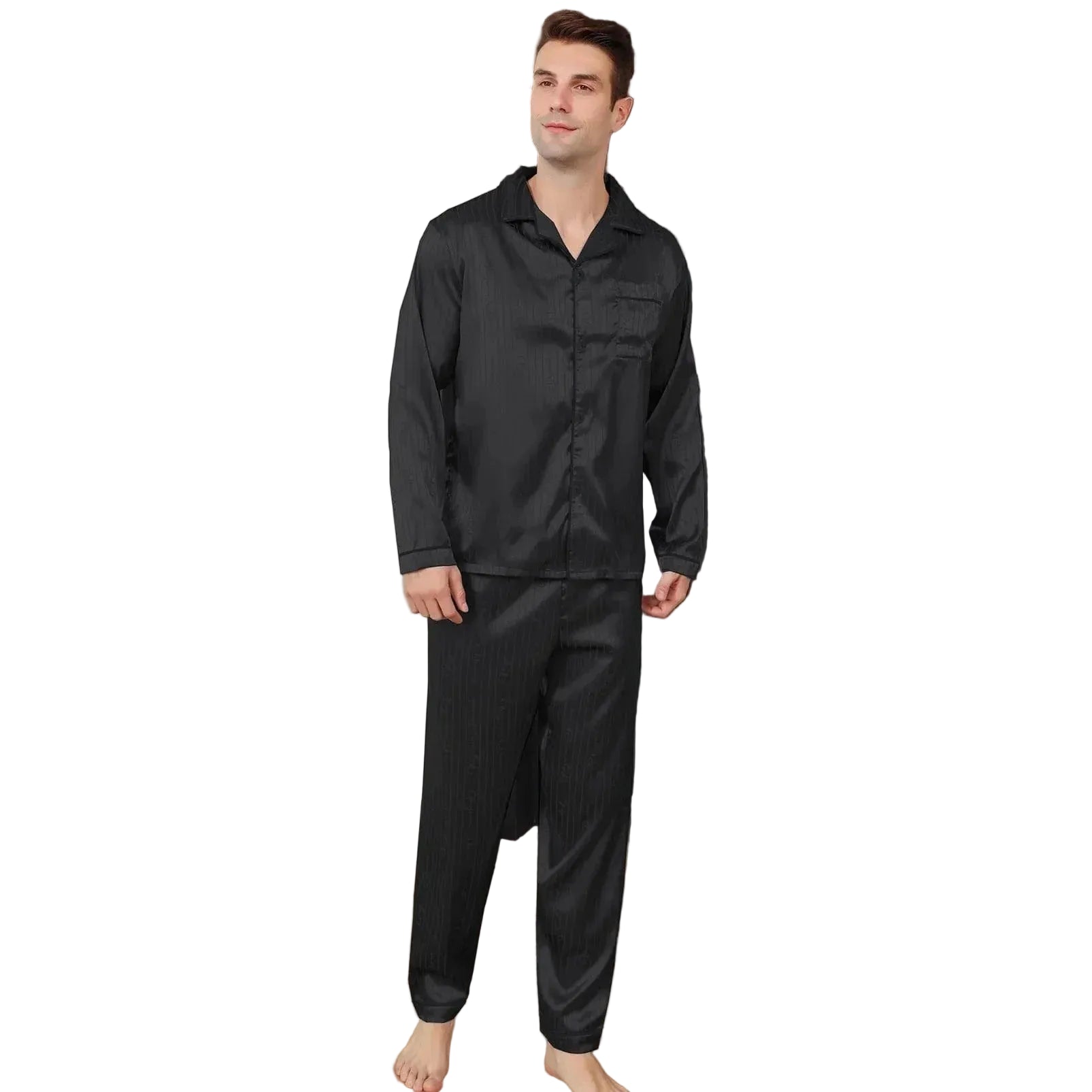 Homme portant le pyjama satin Aymeric pour homme, ensemble noir élégant avec chemise à manches longues et pantalon assorti, col classique et coupe droite, présenté debout pieds nus dans un intérieur moderne, vue de face.