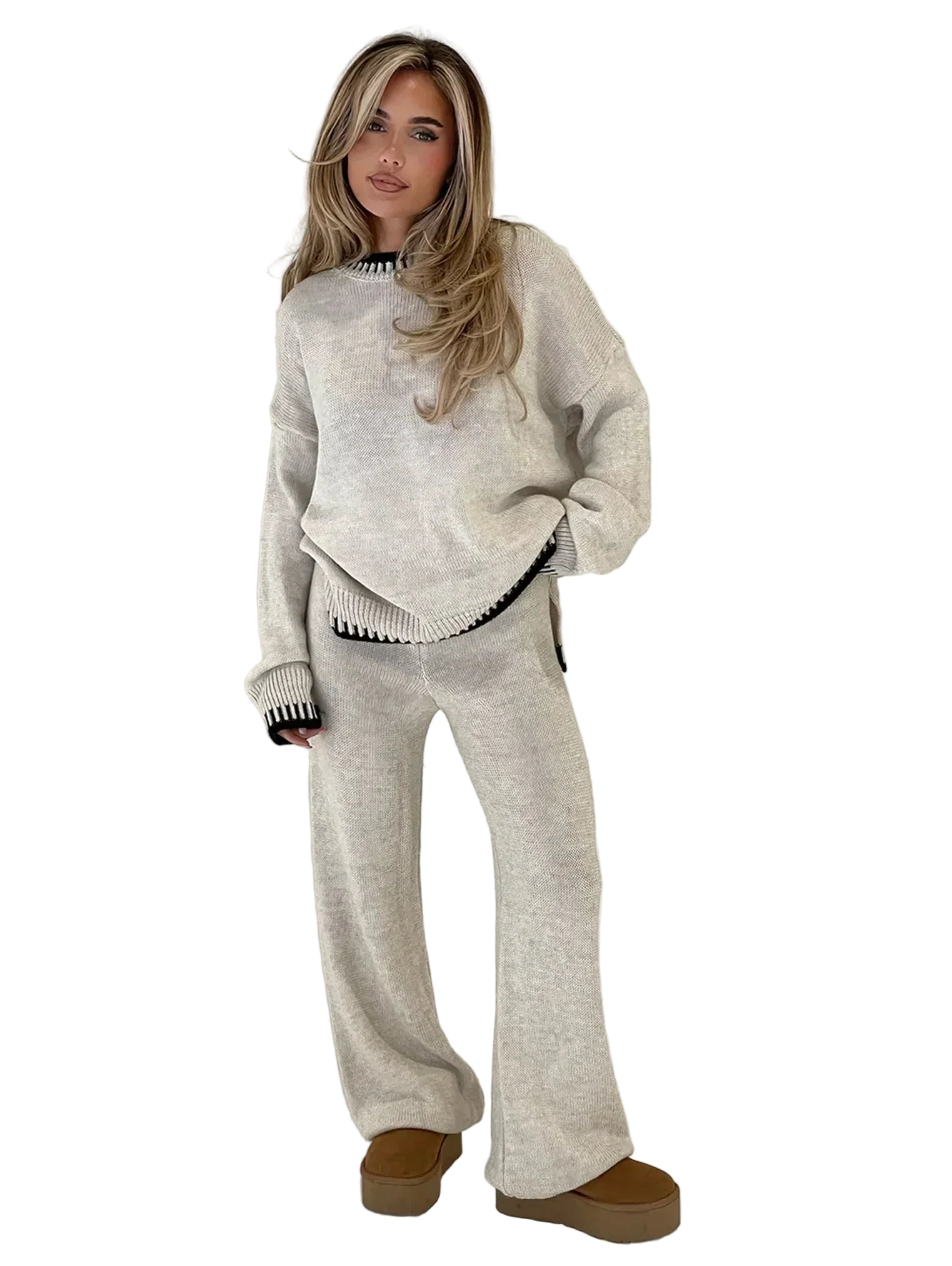 Femme portant un ensemble lounge deux pièces couleur beige chiné, composé d’un pull ample à col rond et manches longues avec détails noirs côtelés, et d’un pantalon large assorti. Tenue douce, élégante et confortable, idéale pour un look casual chic à la maison ou en sortie décontractée.