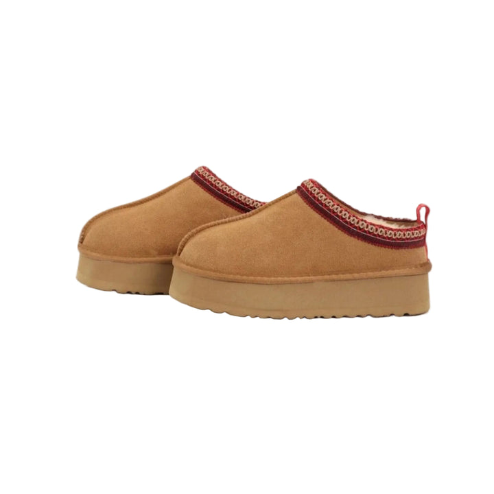 Des pantoufles en daim de couleur camel avec un joli bord décoratif rouge. Ces pantoufles compensées offrent un confort optimal pour vos moments de détente, tout en ajoutant une touche d&