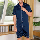 Homme souriant portant un pyjama court en satin bleu marine à manches courtes, avec boutons et passepoils blancs. Ensemble élégant, léger et respirant, idéal pour les nuits chaudes et le confort à la maison.