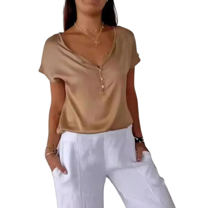 Haut Bliss pour femme, élégant et confortable, coupe fluide à manches courtes, coloris beige satiné avec encolure en V et boutons, porté avec un pantalon blanc pour un look chic et décontracté.