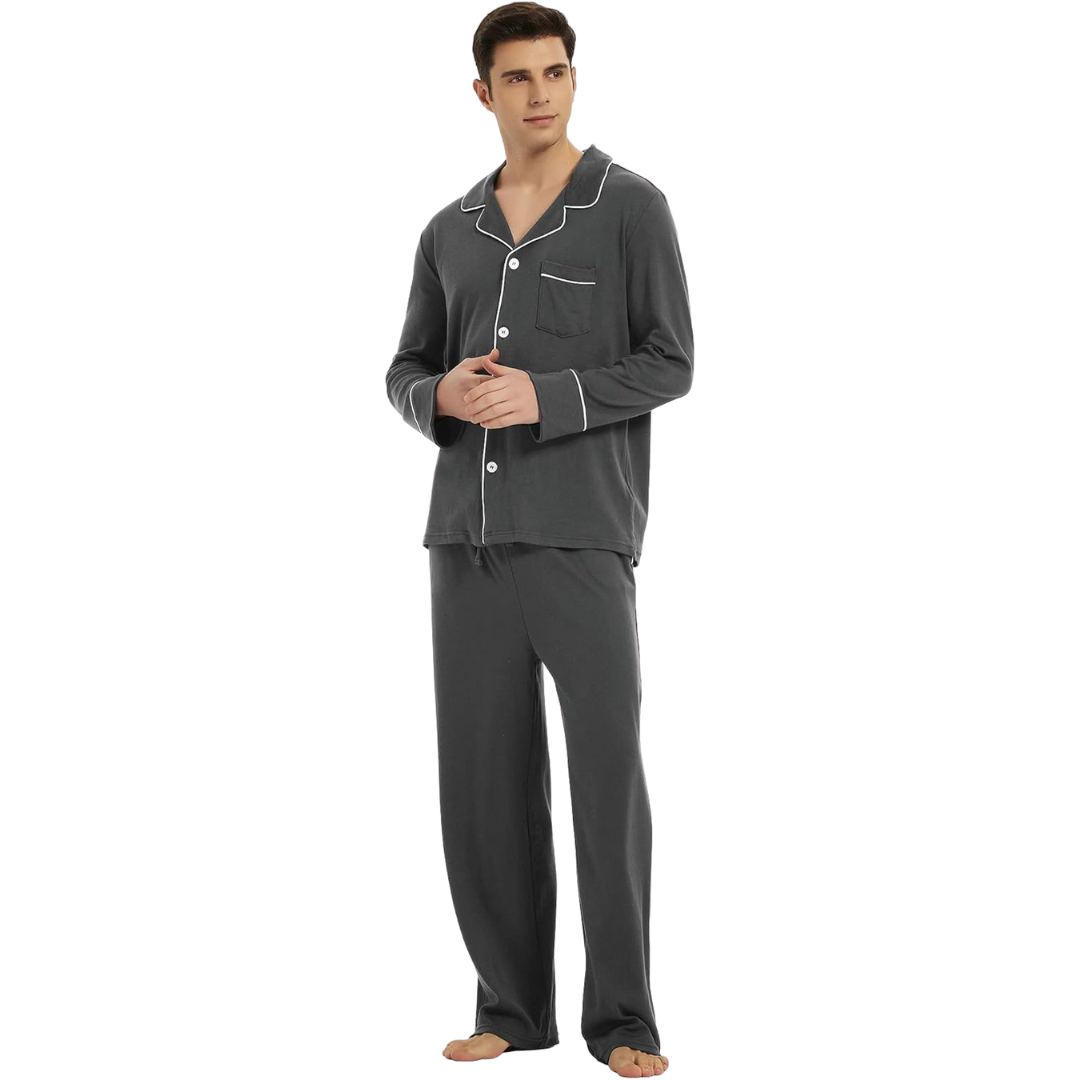 Homme debout portant un pyjama gris foncé avec passepoils blancs, haut à boutons et col classique, accompagné d’un pantalon long assorti. Pyjama confortable, élégant et adapté aux nuits calmes ou aux journées de détente à la maison.