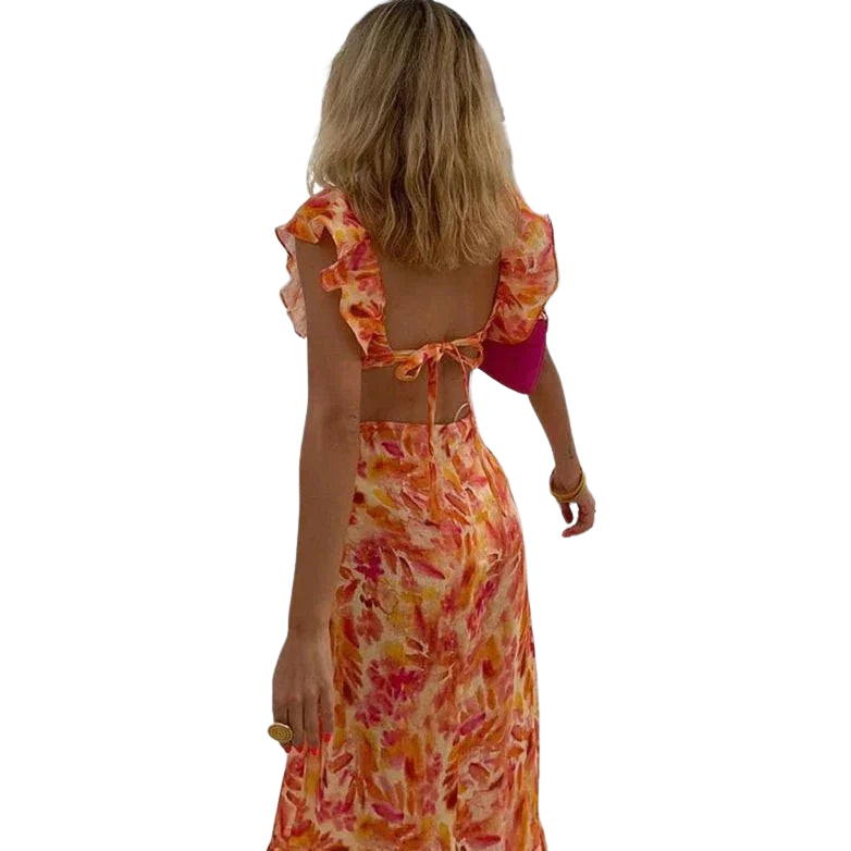 Robe maxi femme Calais fluide à imprimé floral orangé et rose, avec dos ouvert et lien à nouer, portée au bord d’une piscine pour un style élégant, léger et estival.