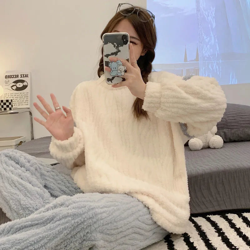 Pyjama femme tendance en peluche, composé d'un haut beige aux manches longues et d'un pantalon bleu clair, avec une texture côtelée. La personne prend un selfie tout en portant le pyjama confortable, créant une atmosphère décontractée et agréable. L'accessoire de téléphone avec un design coloré et les accessoires de style ajoutent à l'aspect moderne et stylé de l'ensemble.
