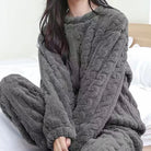 Femme habillée du pyjama Camille en gris foncé, au tissu épais et texturé façon maille torsadée. Un ensemble ultra doux, cosy et agréable, parfait pour se relaxer avec style à la maison.