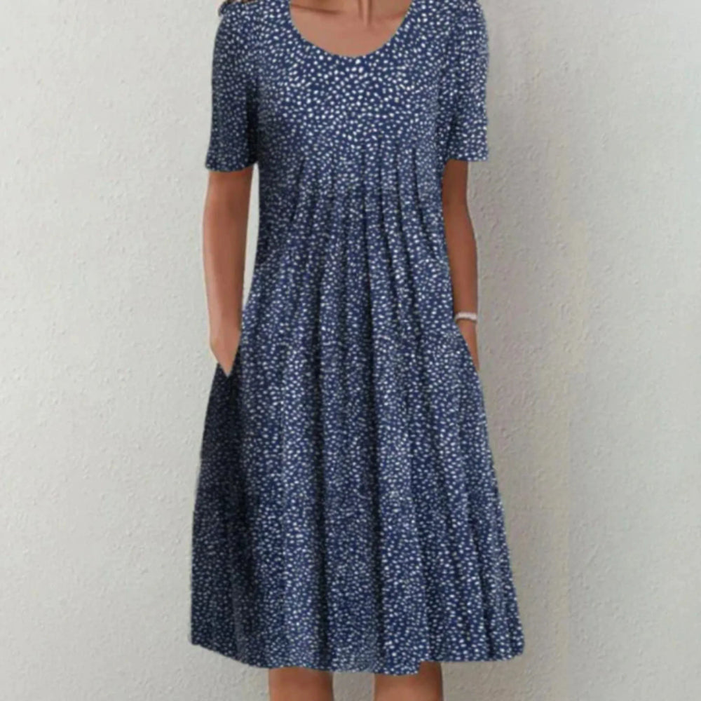 Robe midi femme Charlène légère et élégante, bleu marine à petits motifs blancs, manches courtes, encolure arrondie et coupe évasée avec poches, portée debout.