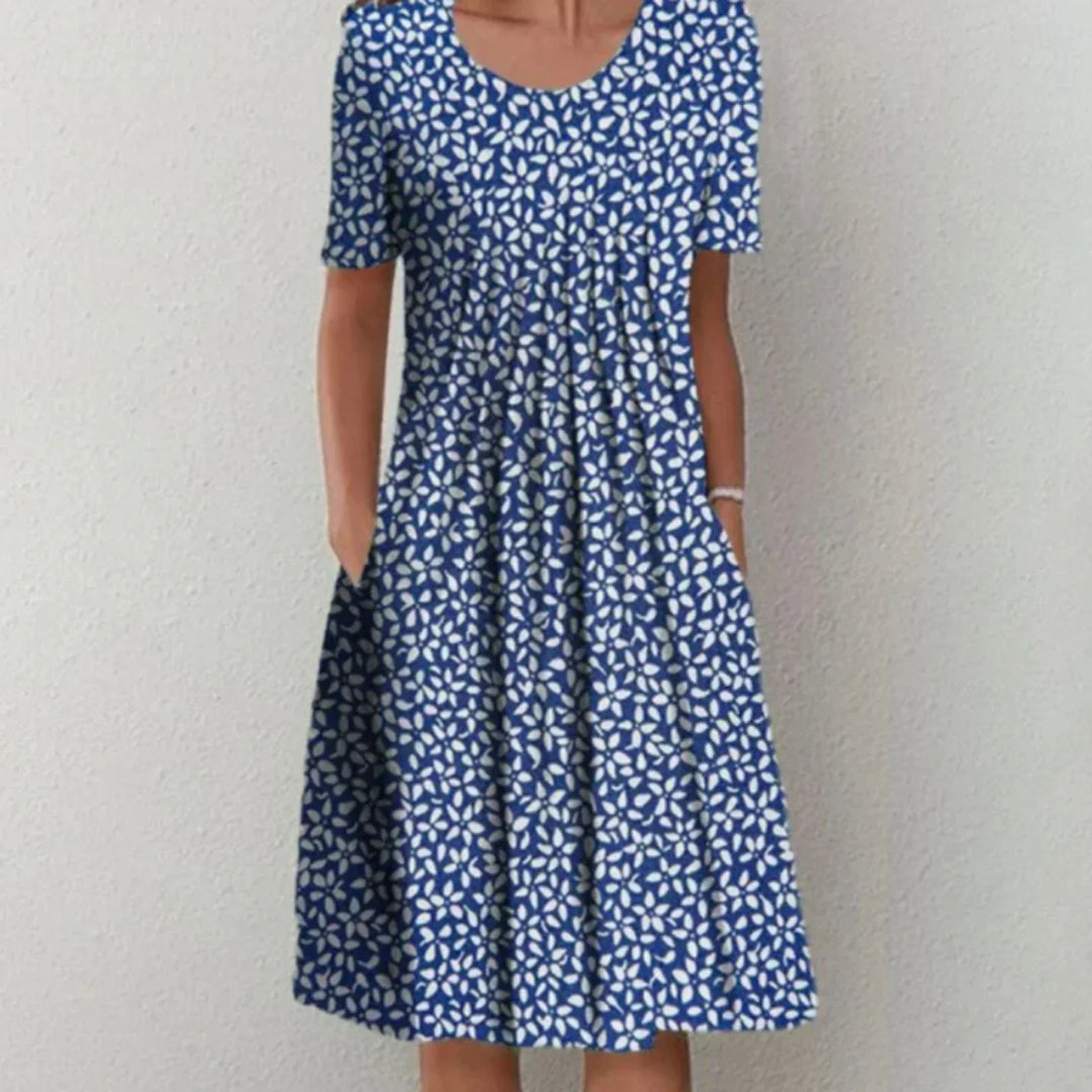 Robe midi femme Charlène légère et élégante, bleu roi à imprimé blanc, manches courtes, encolure arrondie et coupe évasée avec poches, portée debout.
