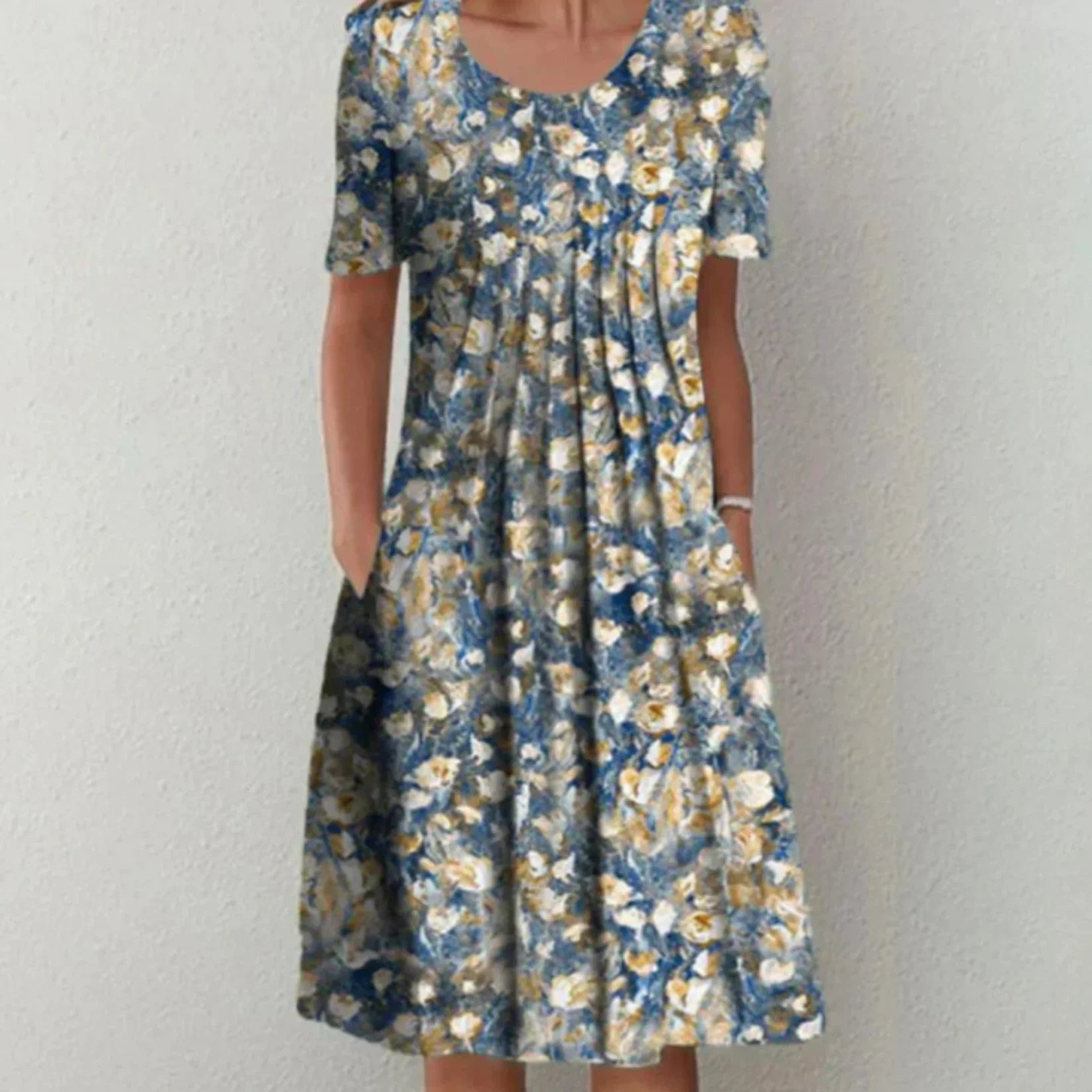 Robe midi femme Charlène légère et élégante, bleu avec imprimé floral blanc et jaune, manches courtes, encolure arrondie et coupe évasée avec poches, portée debout.