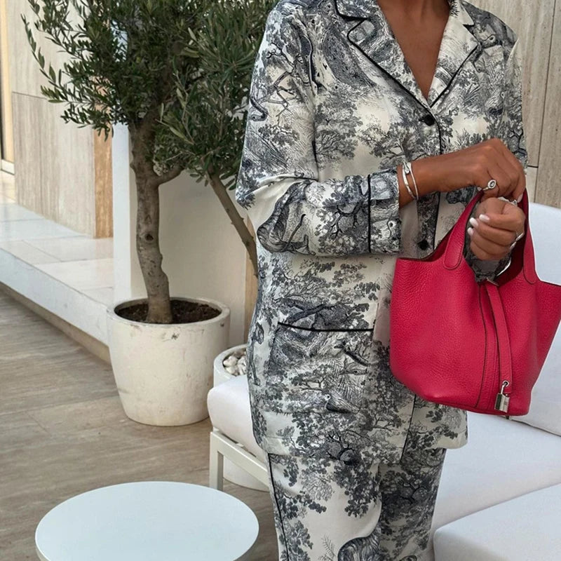 Pyjama femme Charline gris imprimé toile de Jouy, chemise boutonnée à col tailleur avec poches et finitions passepoilées, pantalon long assorti, style élégant et confortable porté en extérieur.