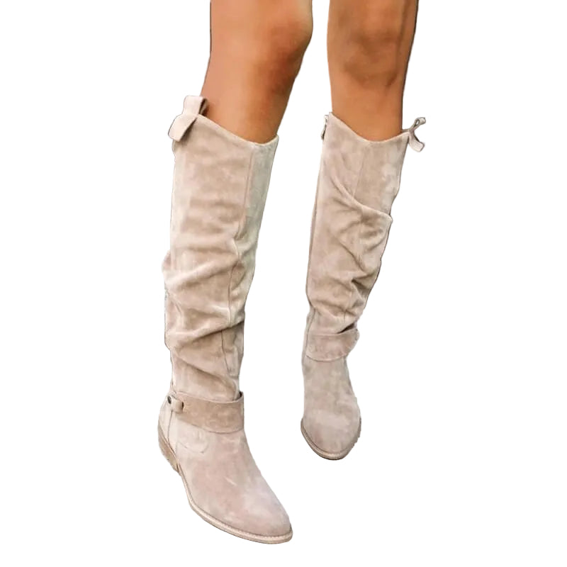 Des bottes en daim beige avec un talon plat et une coupe ajustée, mettant en valeur un look chic et moderne. La tige haute est dotée d'un détail à boucle élégante et d'une finition douce. Ces bottes apportent confort et style pour une allure tendance et raffinée, parfaites pour les saisons plus fraîches.