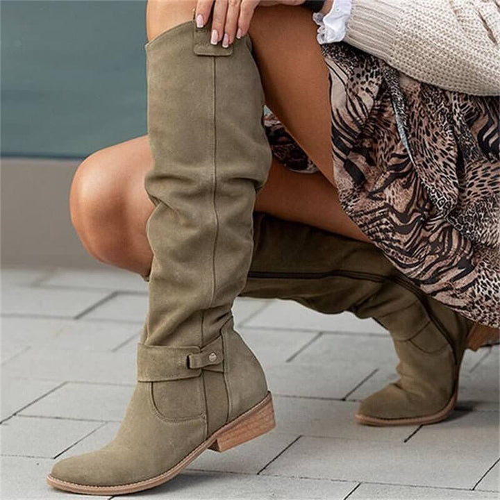 Bottes en daim vert olive à tige haute, dotées de détails élégants comme des boucles et des fermetures zippées. Confortables et modernes, ces bottes sont parfaites pour un look chic et décontracté. Idéales pour compléter une tenue automnale, elles offrent à la fois style et praticité avec leur semelle en bois et leur silhouette raffinée.