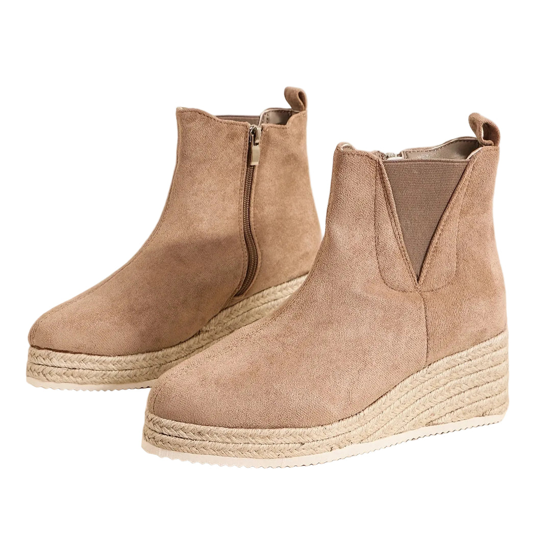 Bottines à talon compensé en daim beige, avec une fermeture éclair sur le côté. Leur design épuré et moderne les rend parfaites pour l'hiver, offrant à la fois confort et style. Idéales pour compléter une tenue élégante et tendance, elles sont parfaites pour les journées froides tout en restant confortables.