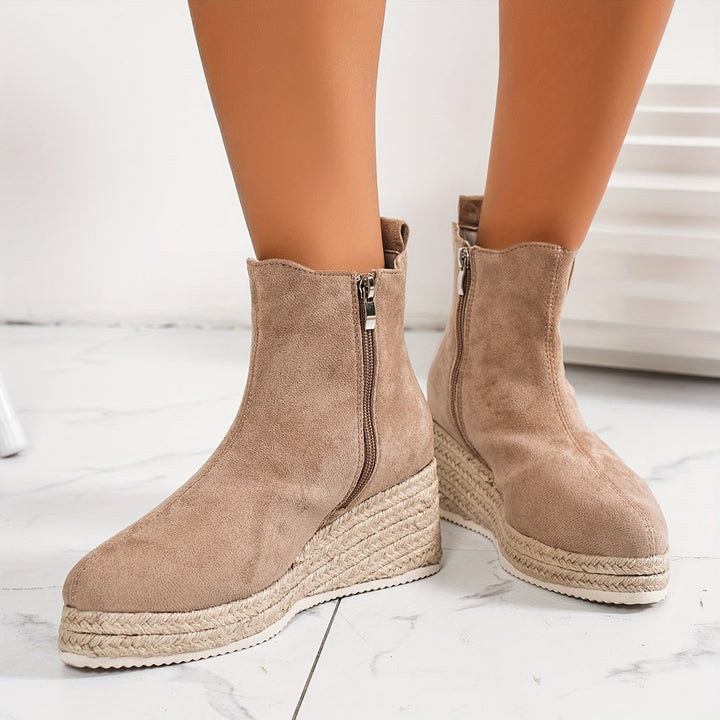Vue rapprochée de bottines beige en daim avec une semelle plateforme en corde et une fermeture éclair latérale, offrant un look moderne et confortable. Ces bottines sont idéales pour l&