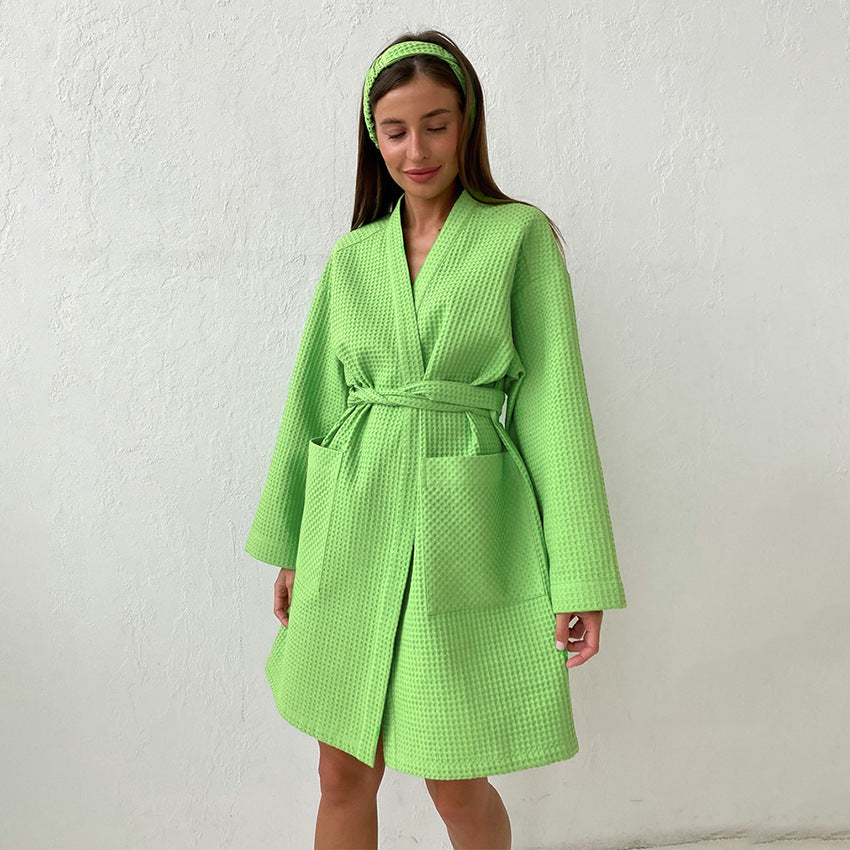 Peignoir en coton pour femme Citron vert vif, tissu gaufré léger, coupe mi-longue avec ceinture et poches, porté debout en extérieur contre un mur clair.