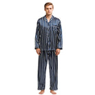 Homme debout portant un pyjama long en satin bleu marine à rayures verticales blanches, composé d’une chemise boutonnée avec poche poitrine et d’un pantalon assorti. Ensemble élégant et confortable, parfait pour des nuits stylées ou la détente à la maison.