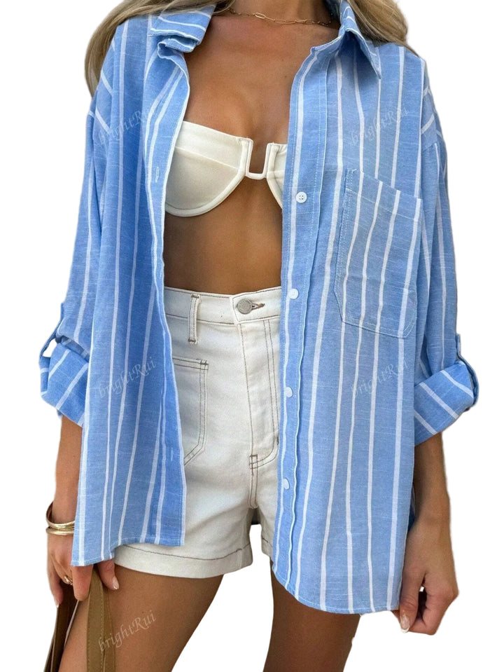 Chemise d’été Clover pour femme, bleu à rayures blanches, légère et confortable, portée ouverte sur un short clair pour un look estival décontracté et tendance.