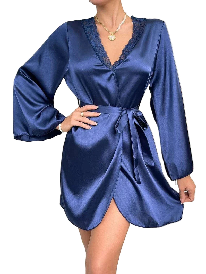 en satin bleu, avec décolleté bordé de dentelle et ceinture nouée à la taille. Le tissu soyeux et la coupe courte soulignent le confort et l’élégance du modèle.