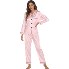 Modèle portant le pyjama femme Coraline rose à rayures, chemise manches longues avec boutons et passepoil contrasté, pantalon assorti coupe droite, style confortable et tendance sur fond blanc.