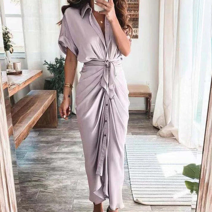 Adoptez un look élégant et aérien avec la robe Deja en couleur lilas. Son design fluide et sa coupe avec un nœud à la taille, accompagné de boutons à l&