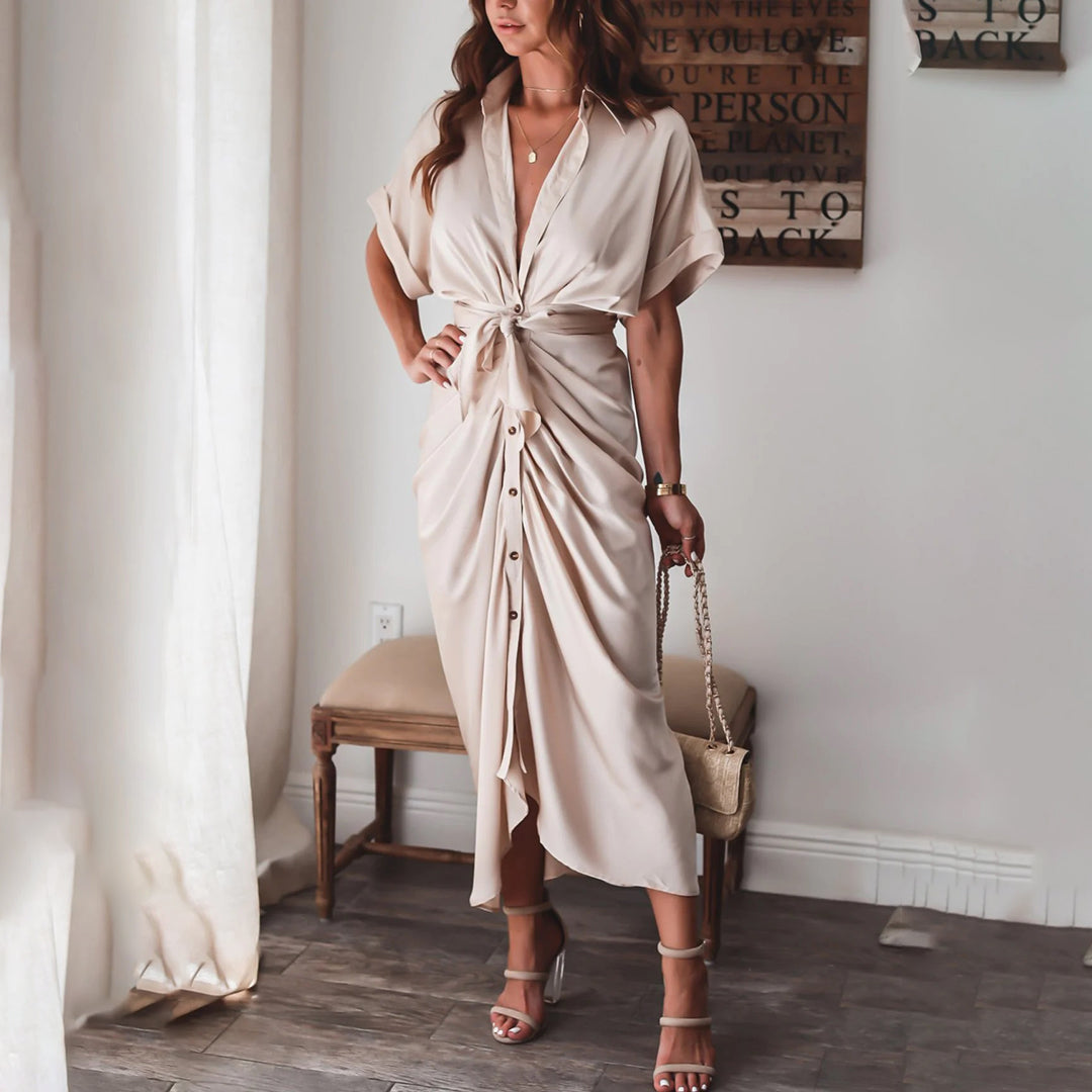 Découvrez la robe Deja en beige, avec son design élégant et sa coupe fluide. Le nœud à la taille et les boutons à l'avant créent une silhouette féminine et raffinée, idéale pour un look estival chic et décontracté.