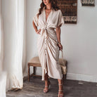 Découvrez la robe Deja en beige, avec son design élégant et sa coupe fluide. Le nœud à la taille et les boutons à l'avant créent une silhouette féminine et raffinée, idéale pour un look estival chic et décontracté.