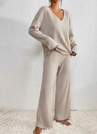 Femme portant l’ensemble Diane en maille côtelée beige, composé d’un haut à col en V ample et d’un pantalon fluide assorti. Une tenue loungewear raffinée, au tissu doux et confortable, parfaite pour se détendre à la maison avec élégance.