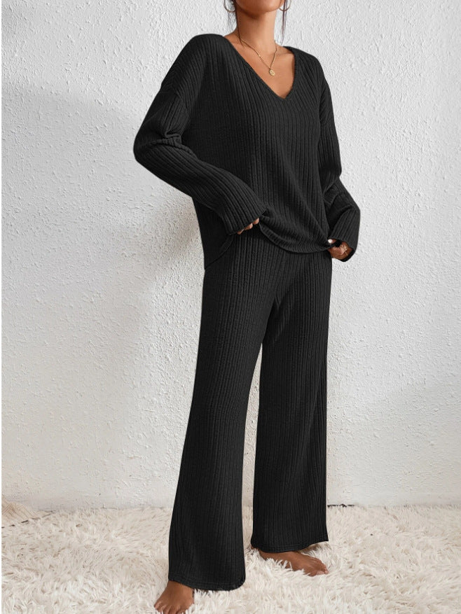 Ensemble deux pièces noir à maille côtelée, composé d’un haut col en V manches longues et d’un pantalon fluide, idéal pour une allure cosy et raffinée à la maison.
