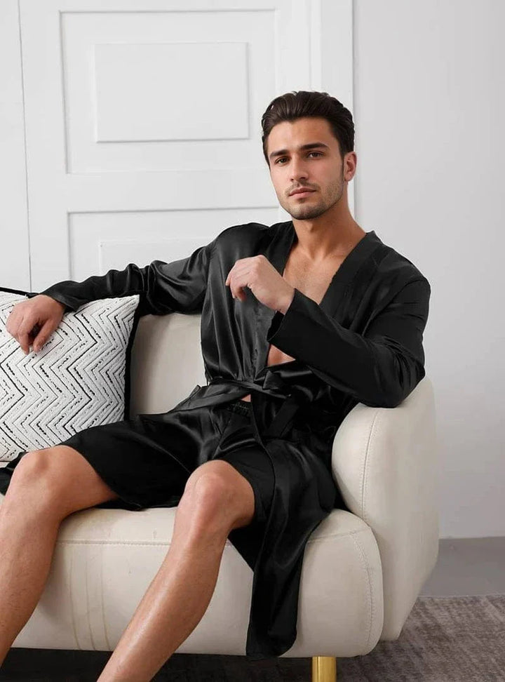 Homme portant le kimono satin homme Dorian noir, à la coupe raffinée avec ceinture ajustable, présenté dans un intérieur moderne pour illustrer un style élégant et agréable au quotidien.