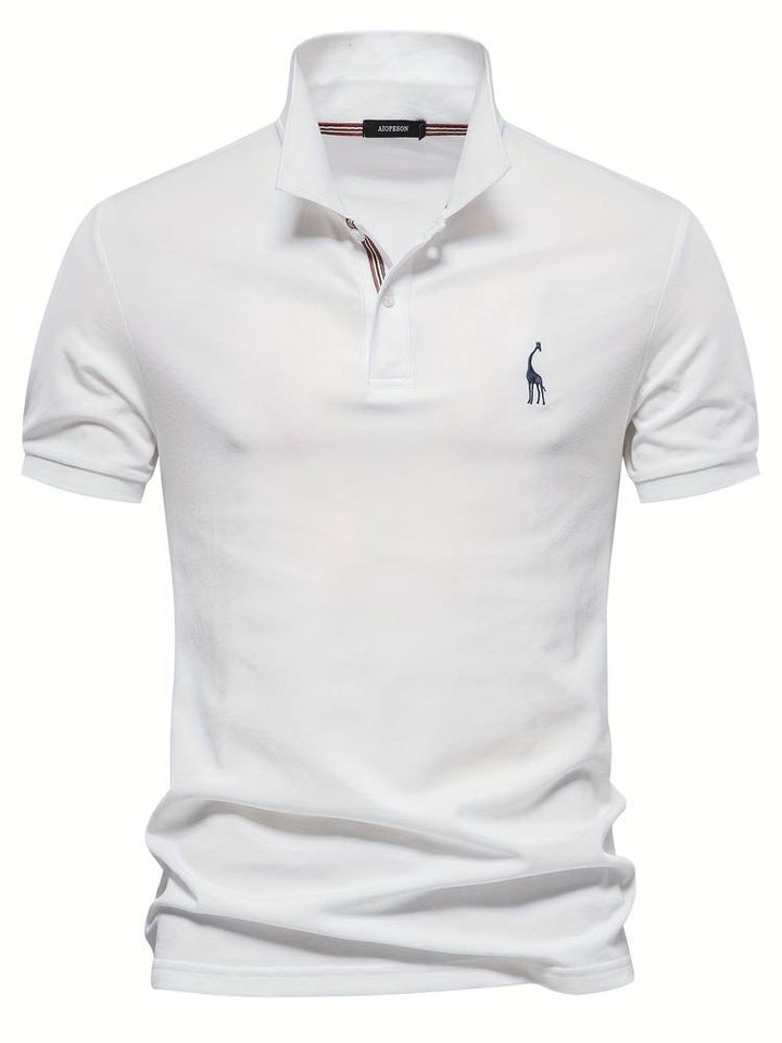 Polo homme blanc, coupe ajustée, avec un logo de girafe bleu sur la poitrine. Le col à rayures rouges et bleues ainsi que les boutons ajoutent une touche de sophistication, parfait pour un look à la fois décontracté et élégant au quotidien.