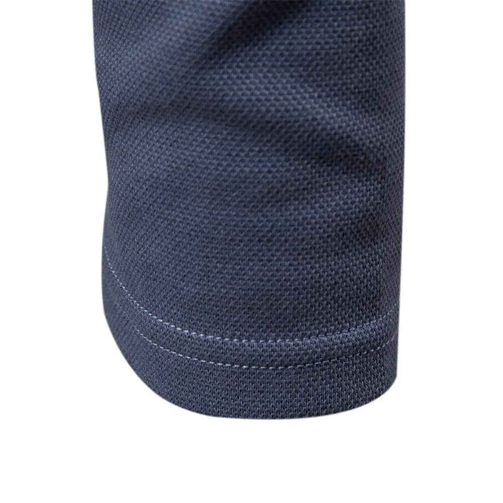 Détail du bas de la manche du polo bleu, mettant en valeur la finition soignée avec un bord côtelé et une texture subtile. Un design élégant et moderne qui assure confort et durabilité.
